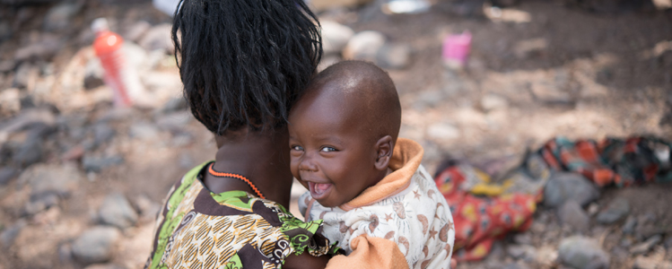 A baby smiles at the camera