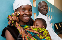 Photo of a woman and man smiling with a baby.