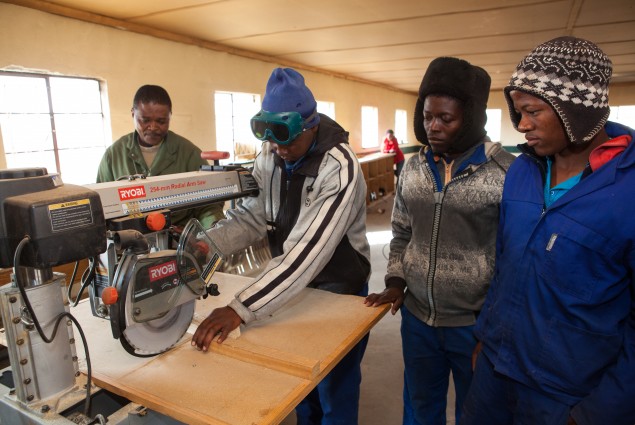 A group of men standing around a workbench